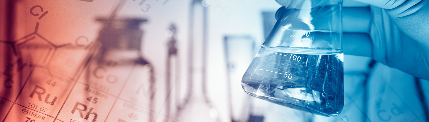 Gloved hand holding beaker in front of backdrop showing periodic table and glassware