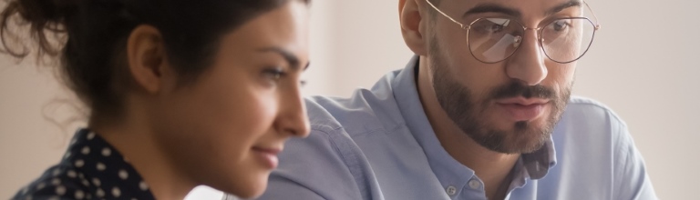 Two professional people looking at a laptop screen. 